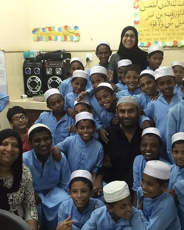 Children of Give Light Home in blue kurtas, smiling with their teachers